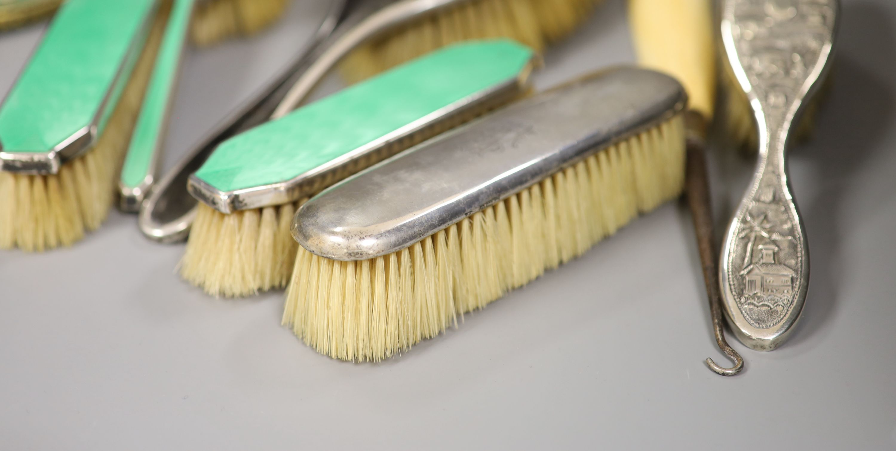 A guilloche enamel and silver-mounted three-piece brush and comb set, three other silver-mounted brushes and five other items,